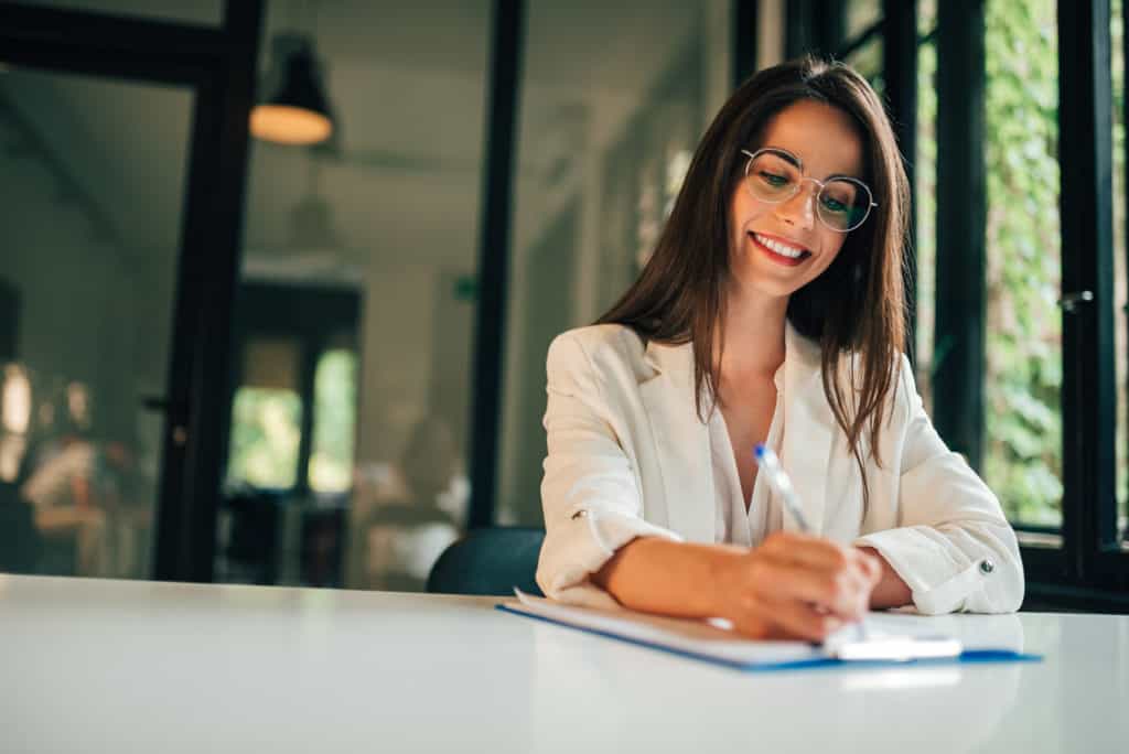 woman writing on a piece of paper at a counter